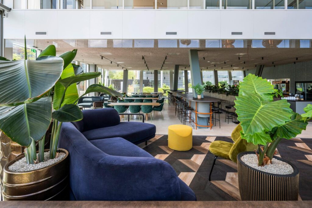 Moderne, open kantoorlobby aan de David Ricardostraat met kleurrame meubels, grote planten en veel natuurlijk licht.